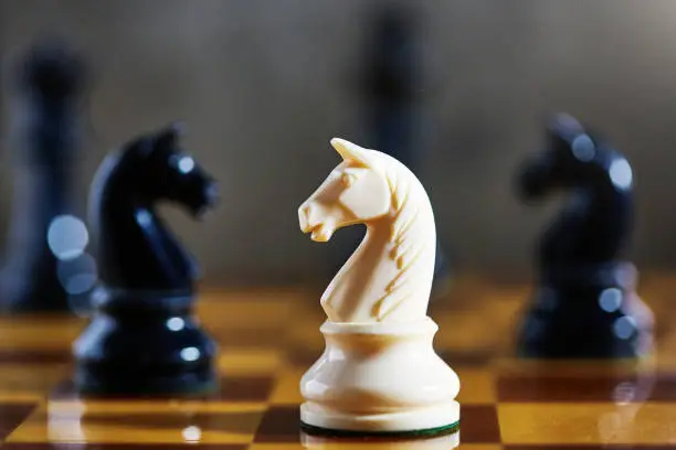 Close-up of white knight in a chess game. White knight is a business concept, meaning a company being acquired by a "friendly" company as a defense against a hostile takeover.