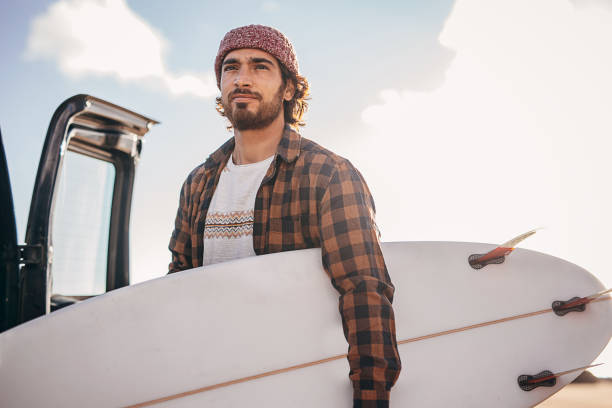 istock Hipster surfer taking surfboards from the car trunk 1393549428