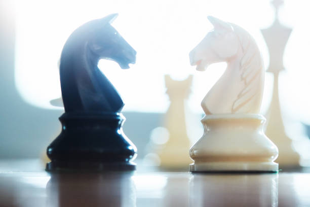 istock Atmospheric shot of rival knights confronting each other during a chess game, back lit by a window 1393549442