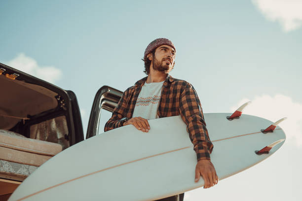 istock Hipster surfer taking surfboards from the car trunk 1393549452