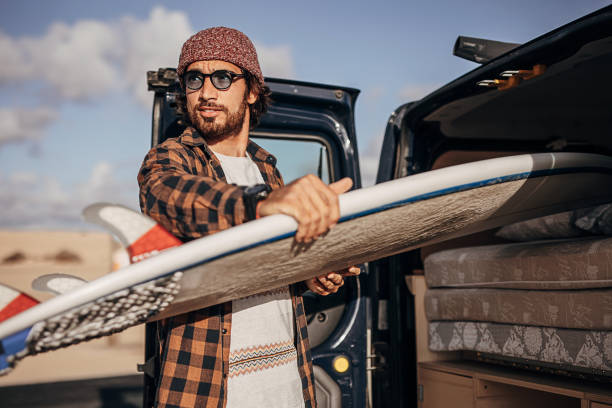 istock Hipster surfer taking surfboards from the car trunk 1393549559