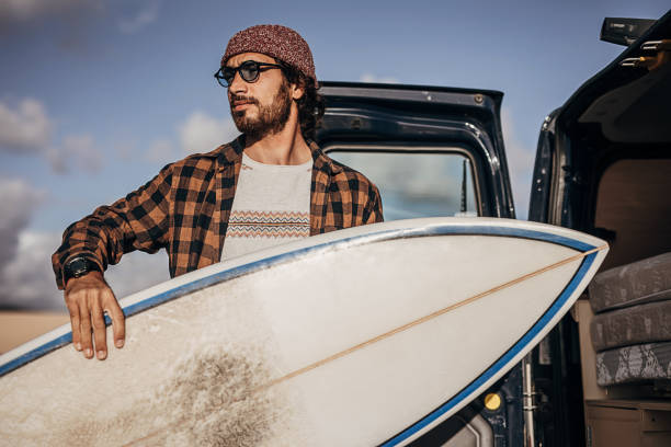 istock Hipster surfer taking surfboards from the car trunk 1393549628