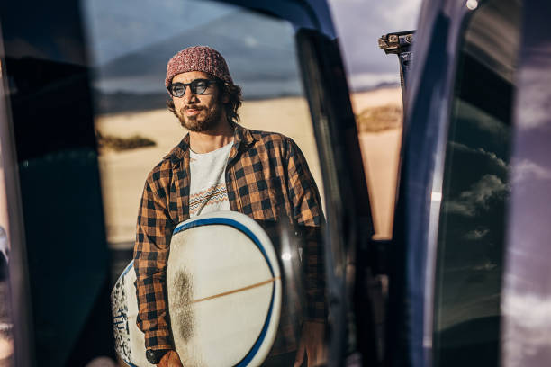 istock Man surfer taking surfboard from the car and going to the beach 1393549662