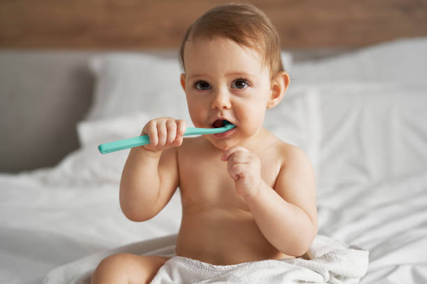 kleines baby beginnt nach dem bad mit dem zähneputzen - hygiene dental hygiene human teeth child stock-fotos und bilder