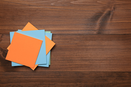 Stack of colorful stickers on wooden table, top view. Space for text