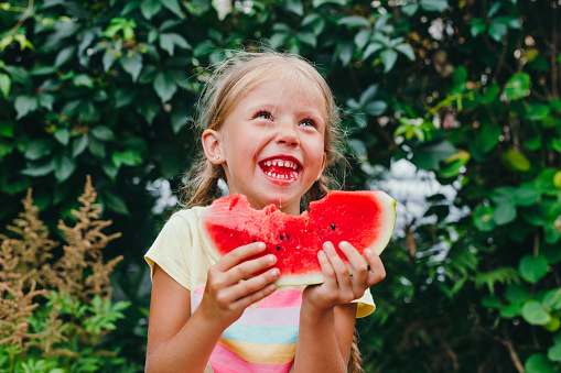 Happy funny kid eats watermelon outdoor. Summertime