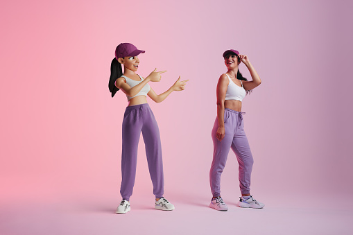 Cheerful young woman smiling at her metaverse avatar in a studio. Happy young woman standing next to the 3D simulation of herself. Sporty young woman exploring virtual reality.