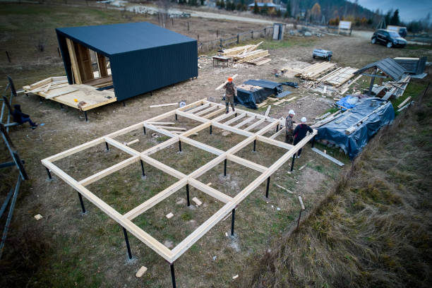 Man worker building wooden frame house on pile foundation.
