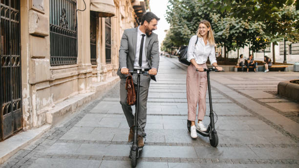 istock Two business people going to work with electric push scooter, laughing and having fun. Sustainable transportation 1393557905