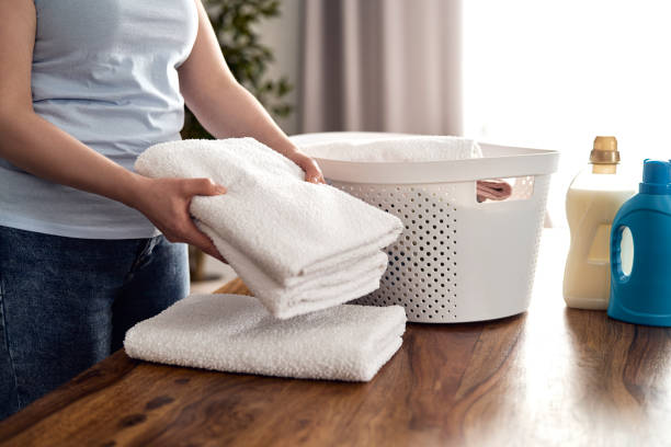 Close up of caucasian woman folding fresh towels at home stock photo