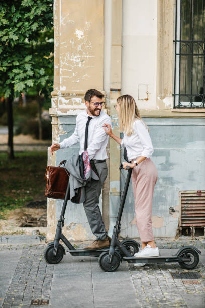istock Two business people going to work with electric push scooter, laughing and having fun. Sustainable transportation 1393558039