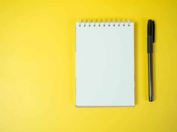 istock Notebook and pen, on a yellow background. Top view copy space 1393561439