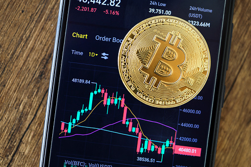 Bitcoin cryptocurrency coin on trading charts of the Binance Crypto exchange smart phone app display screen.