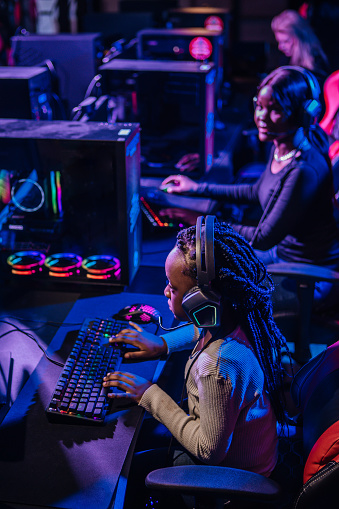 Beautiful young black mother and daughter playing online games in a Esports Gaming Cafe