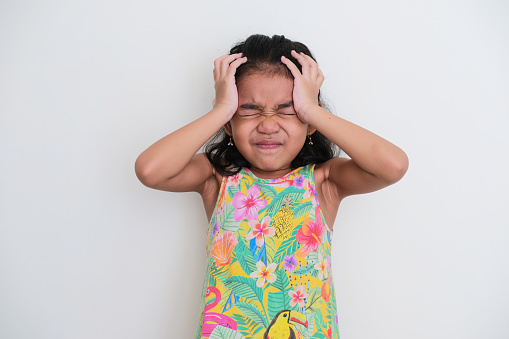 Asian kid girl showing stressed expression with both hand on her head