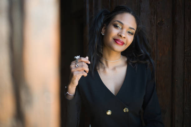 Portrait of a fashionably dressed young black woman. She is a successful young entrepreneur. She loves luxury. She stands in front of an old wooden door in Venice.