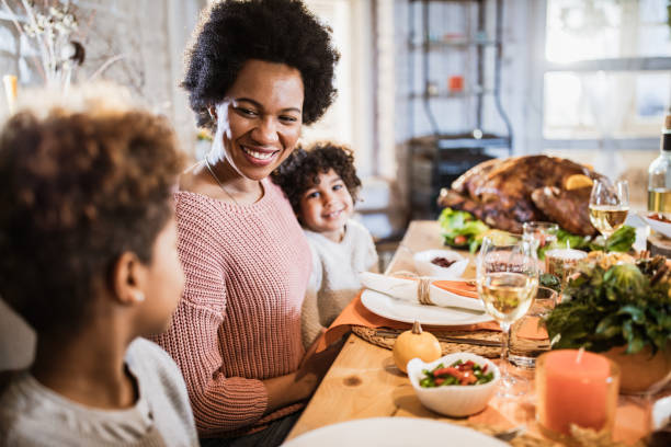 istock Happy black single mother and her daughters on Thanksgiving day at dining table. 1393565527