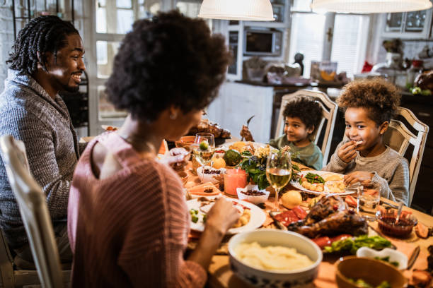 istock Happy black parents and their kids talking during dinner at home. 1393566080