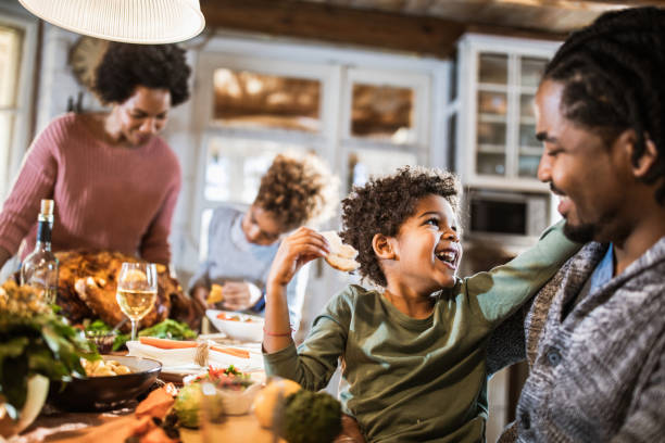 istock Happy black boy talking to his father at Thanksgiving dining table. 1393566724