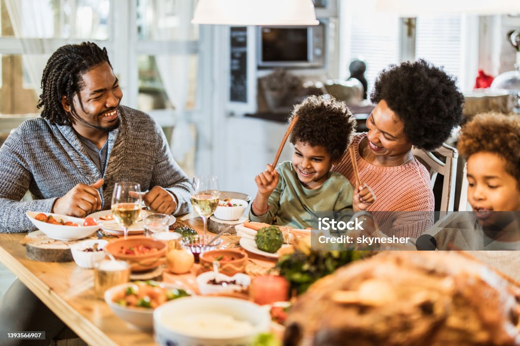 Happy Black Family Enjoying During Thanksgiving Dinner At Dining Table