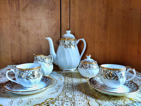 Picture of a beautiful tea set having cups kettle utensils for milk and sugar shot at a restaurant