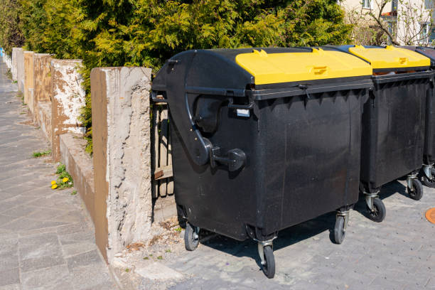 istock Two trash bins with yellow lids are along the concrete wall. 1393567078