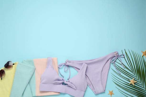 istock Beach towel, swimsuit and sunglasses on light blue background, flat lay. Space for text 1393567131