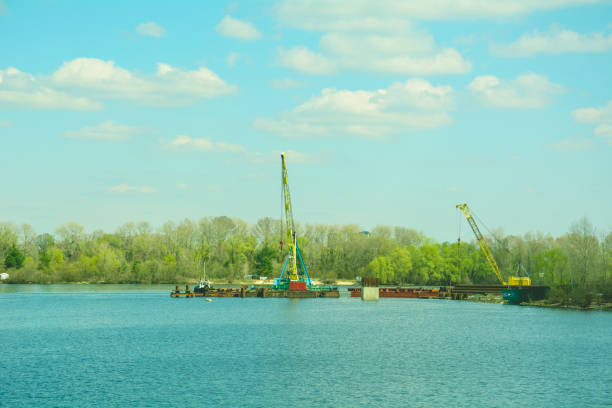 istock Construction large floating cranes build a large bridge on a beautiful river 1393567218