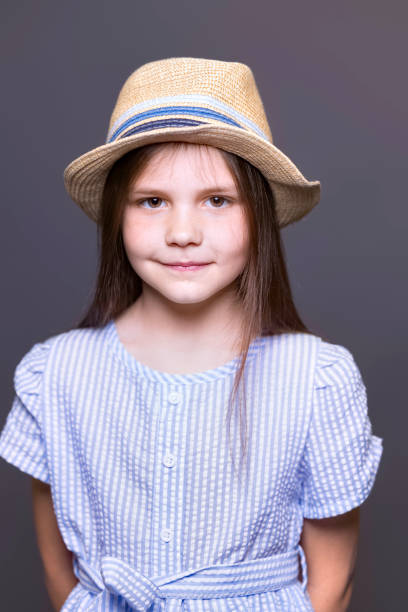 Brown-haired girl of seven wearing a striped blouse and jaunty hat.