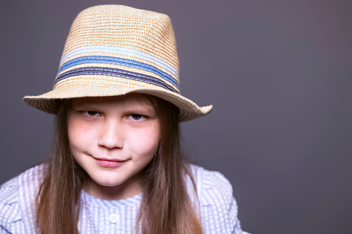 portrait of smiling girl with long dark hair in straw hat against green wall