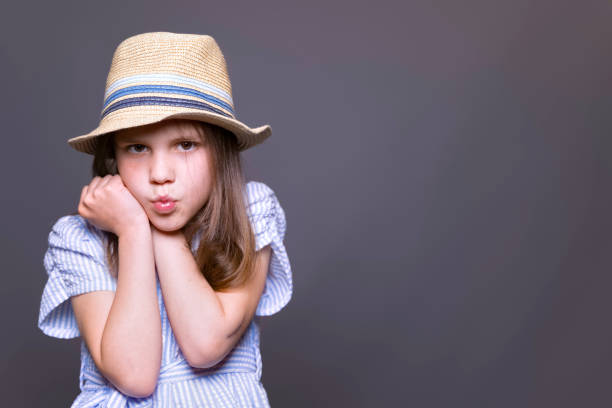Brown-haired girl of seven wearing a striped blouse and jaunty hat.