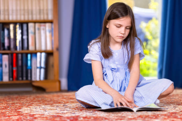 istock Cute young girl sitting on the floor reading 1393568309