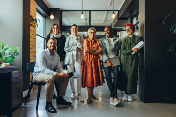 une équipe d’affaires performante souriant à la caméra dans un bureau - vêtement modeste photos et images de collection