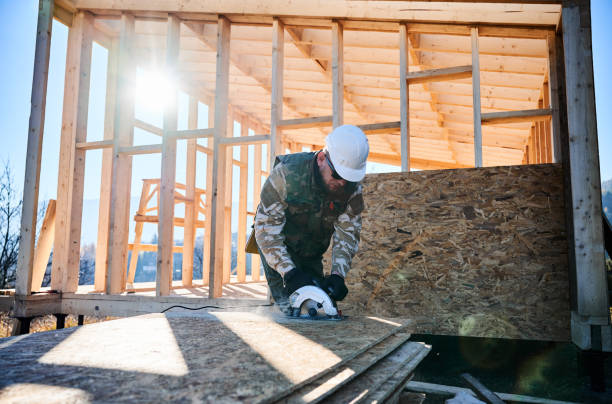 istock Carpenter using circular saw for cutting OSB board for building wooden frame house. 1393572446
