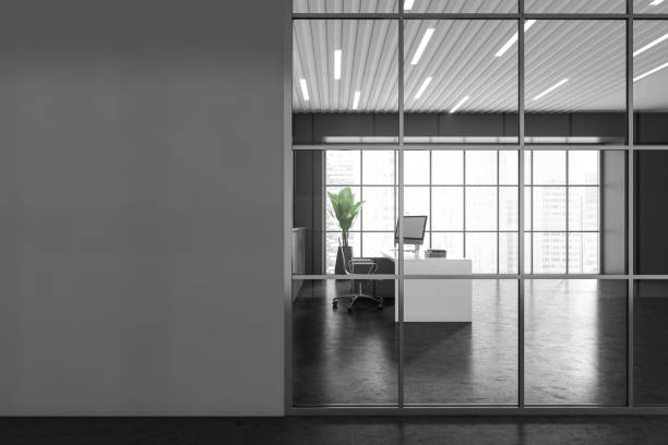 istock Front view of dark grey office room interior with ceo table, desk with desktop computer, armchair, panoramic windows, concrete floor. Mockup empty wall. AD Concept. City view. 3d rendering 1393574404