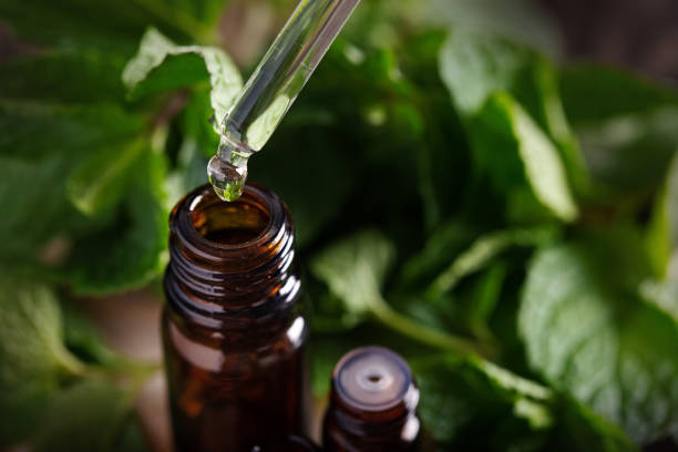 istock Essential oil falling from glass dropper into amber bottle 1393579633