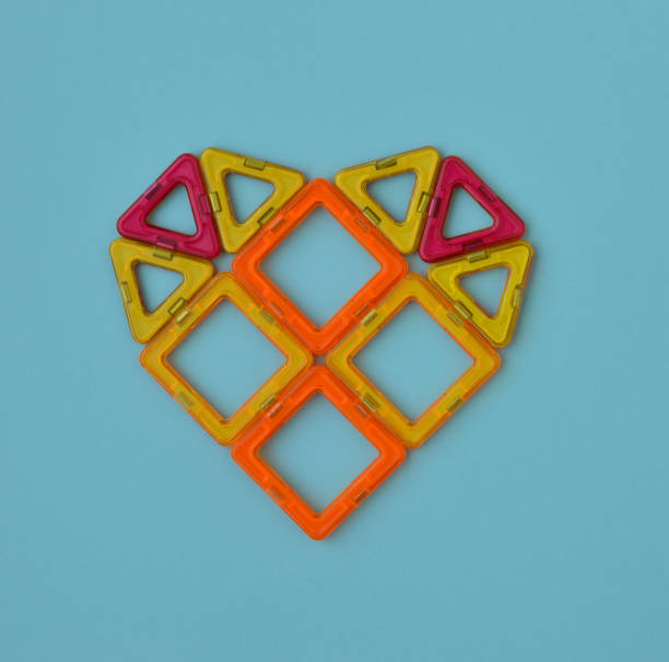 istock Heart-shaped, lined with multicolored parts of a magnetic constructor on blue background. 1393580878