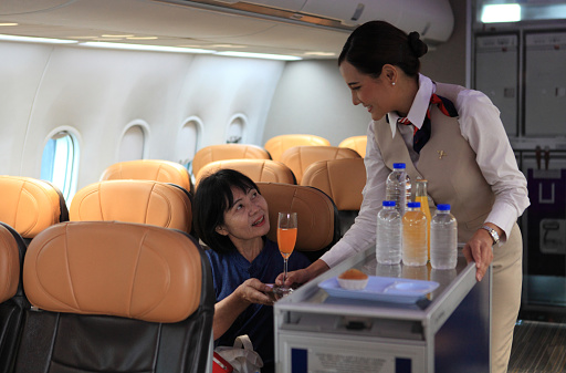 Cabin crew pushing service cart and serve to customer on the airplane during flight. hostess service on plane