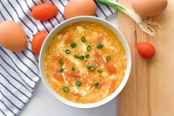 Tomato egg drop soup in a white bowl.