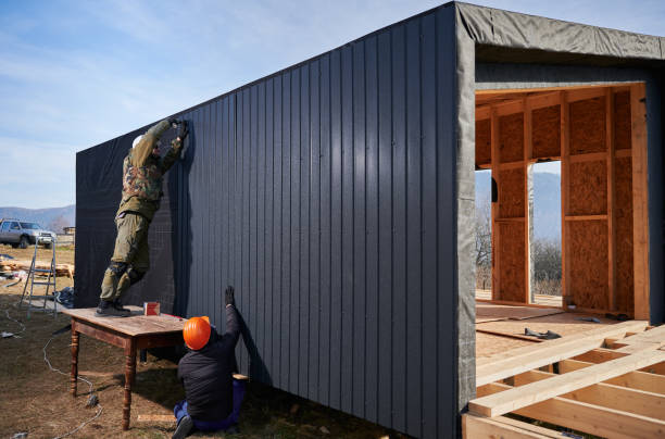 istock Builder installing corrugated iron sheet used as facade of future wooden frame house. 1393584036