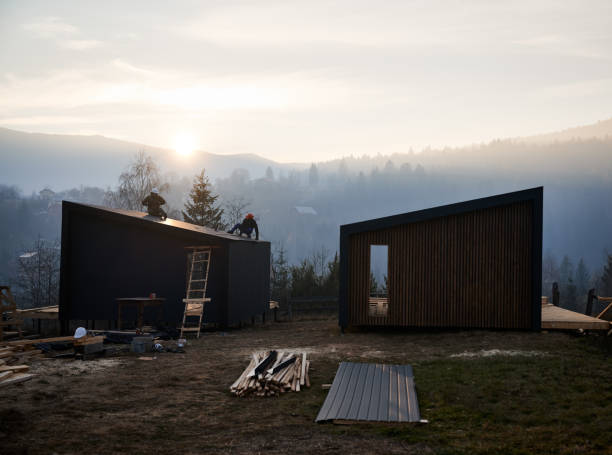 istock Builder installing corrugated iron sheet used as facade of future wooden frame house. 1393584114