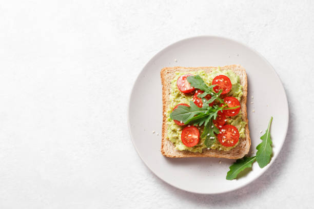 istock Avocado rye bread toast with cherry tomatoes and arugula on bright background. Healthy appetizer, breakfast, lunch or snack. Vegan food concept. Top view, copy space 1393584316