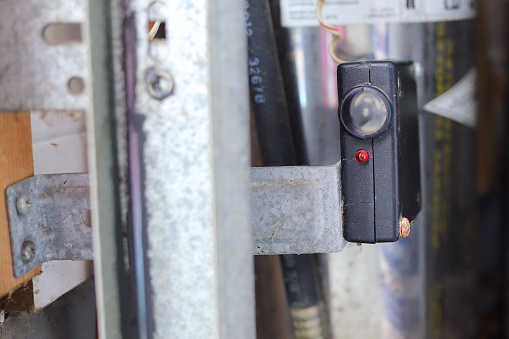 Close up of a garage door photo eye sensor