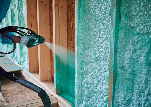 Trabajador pulverizando espuma de poliuretano para aislar la casa de marco de madera. photo