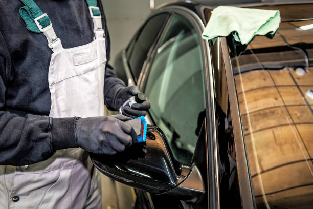 Car service worker applying nanocoating on a car detail. stock photo
