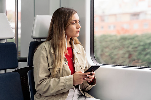 Stock photo of young attractive girl listening to music wearing headphones and looking at her phone.