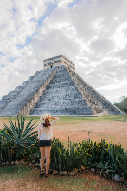 Woman on the background of Chichen Itza pyramid in Mexico Rear view of young Caucasian  woman in hat  standing  on the background of Chichen Itza pyramid in Mexico chichen itza photos stock pictures, royalty-free photos & images