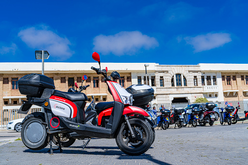 Valencia-Spain April 23, 2022. Various electric motorcycles for rent parked on a sidewalk waiting customers.