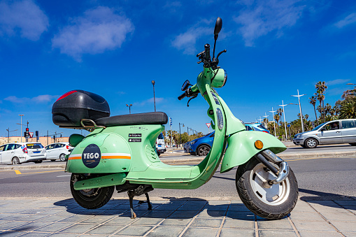 Valencia-Spain April 23, 2022. YEGO green electric motorcycle waiting a customer for rent parked on a sidewalk.