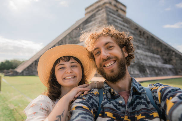 paar macht selfie auf dem hintergrund der chichen itza pyramide in mexiko - travel to mexico stock-fotos und bilder